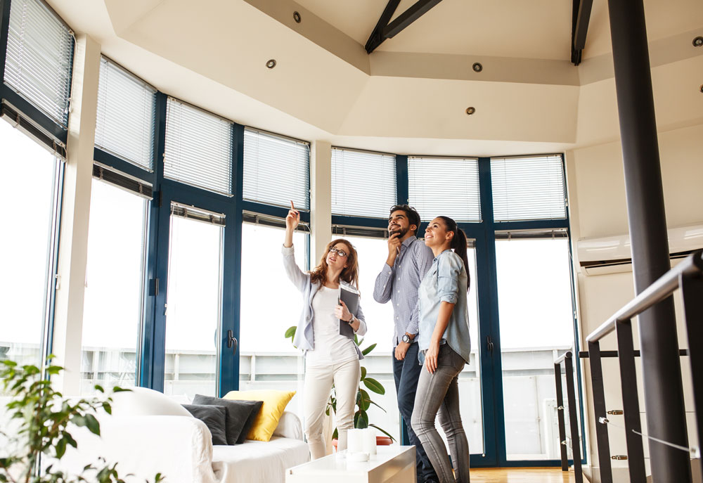 Female real estate agent pointing out ceiling to buyers